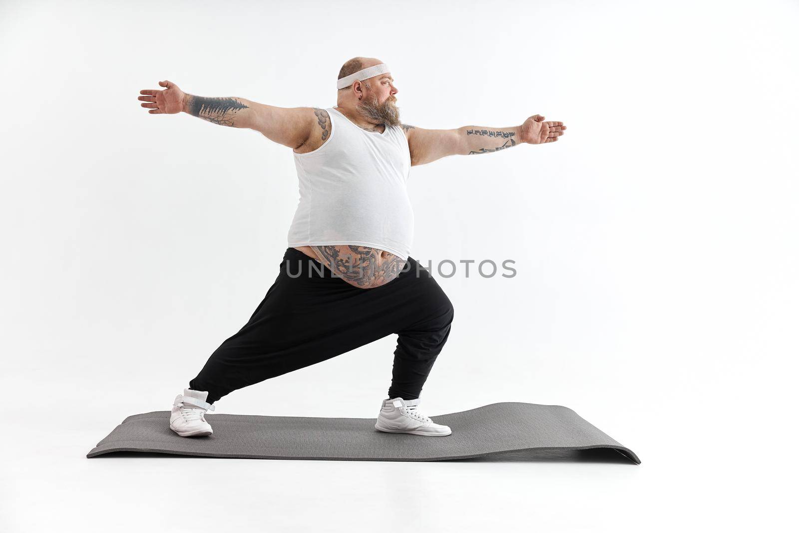 Sporty fat man with beard and tattoos is doing yoga by Yaroslav_astakhov