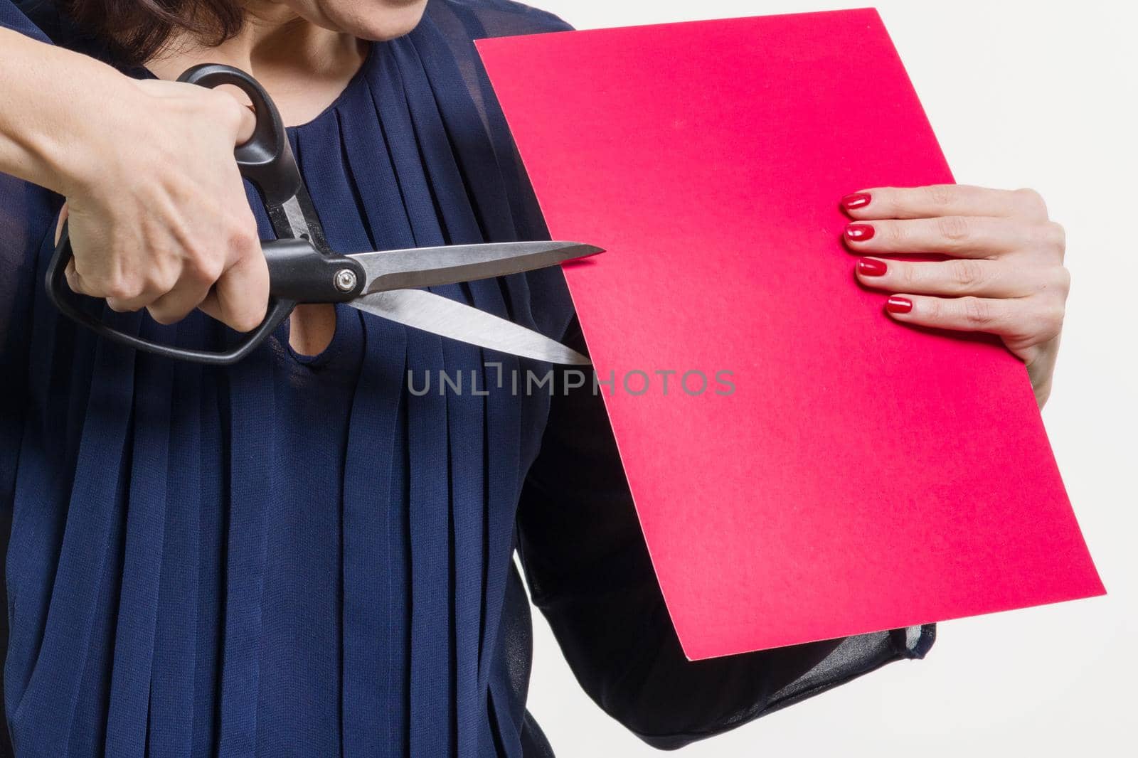 A woman holds scissors and a sheet of paper, cuts paper. White background
