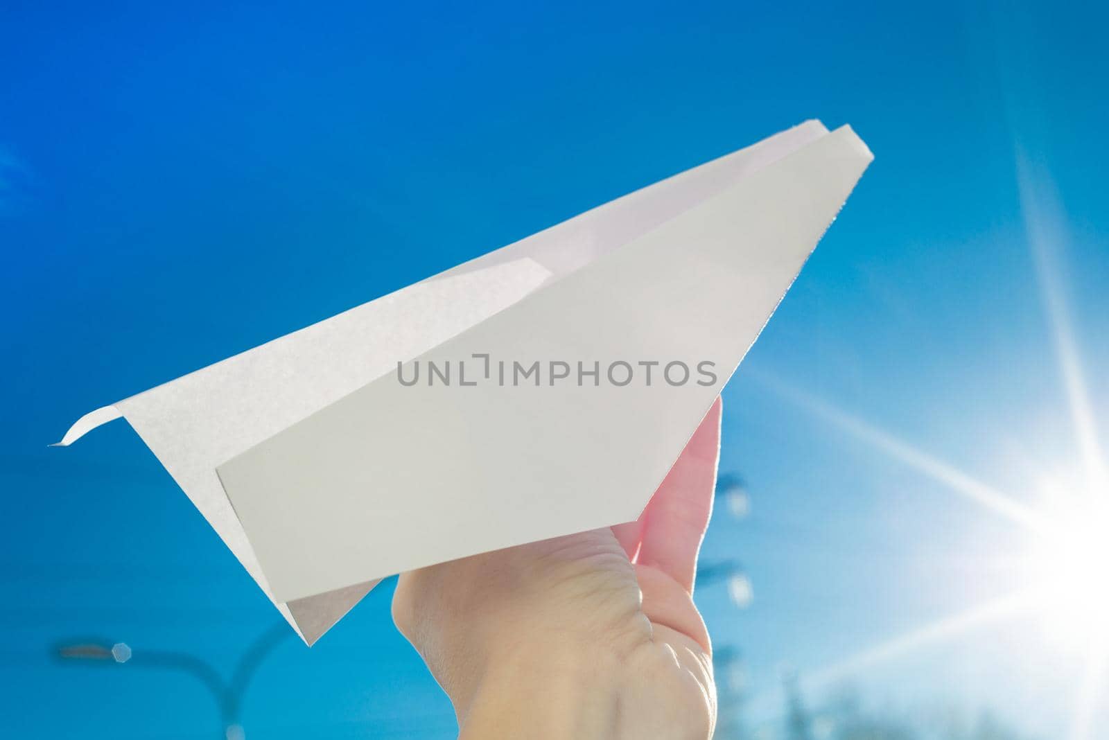 Abstract paper plane, in hand, blue sky, sun background