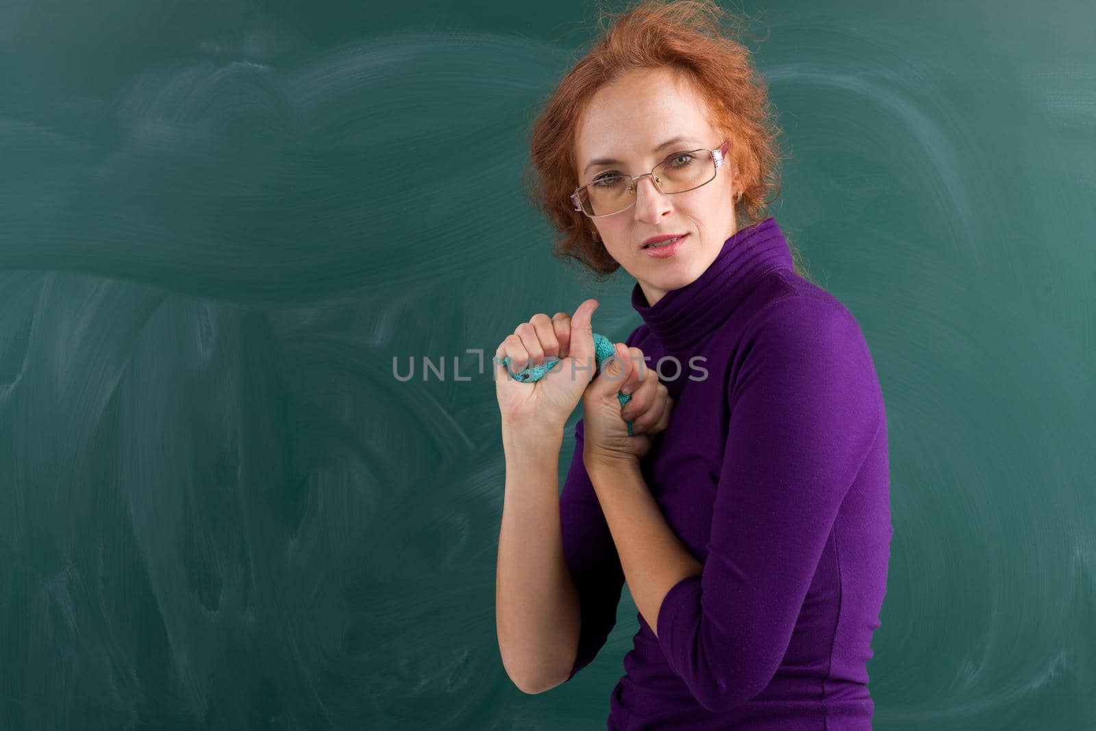 Angry teacher wringing out rag at blackboard by kolesnikov_studio