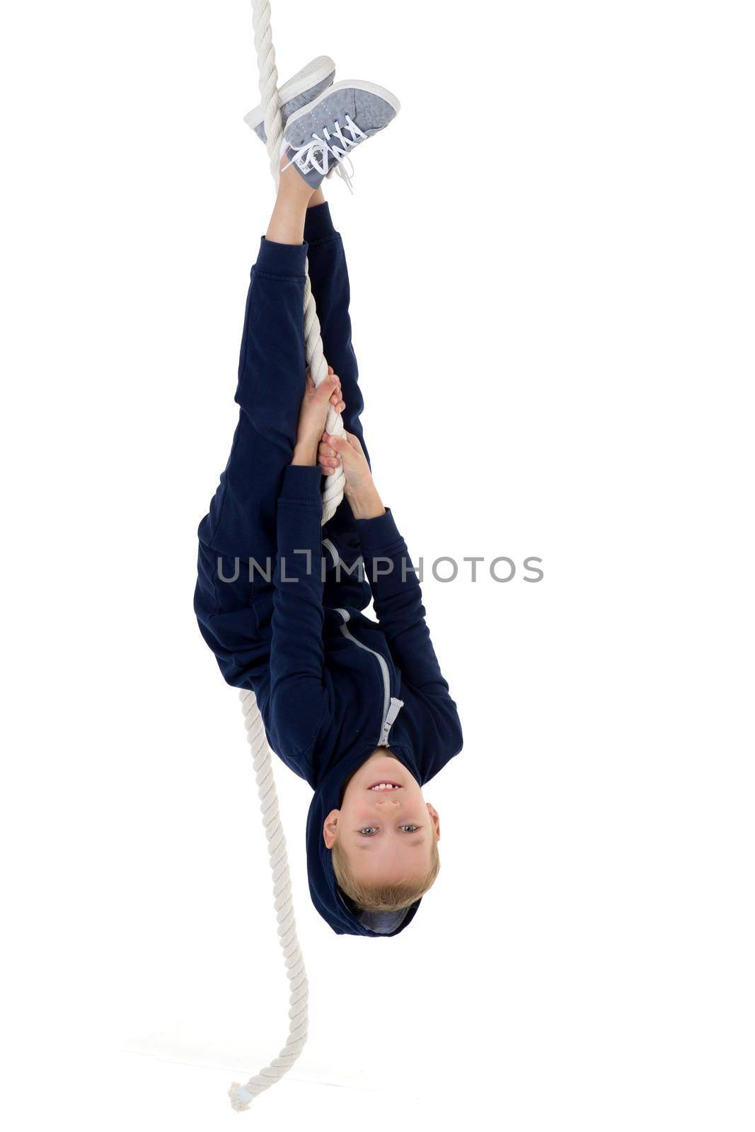 Active boy swing upside down on the rope. Kid playing and having fun doing activities. Happy child wearing casual clothes isolated on white background. Happy childhood, active lifestyle concept
