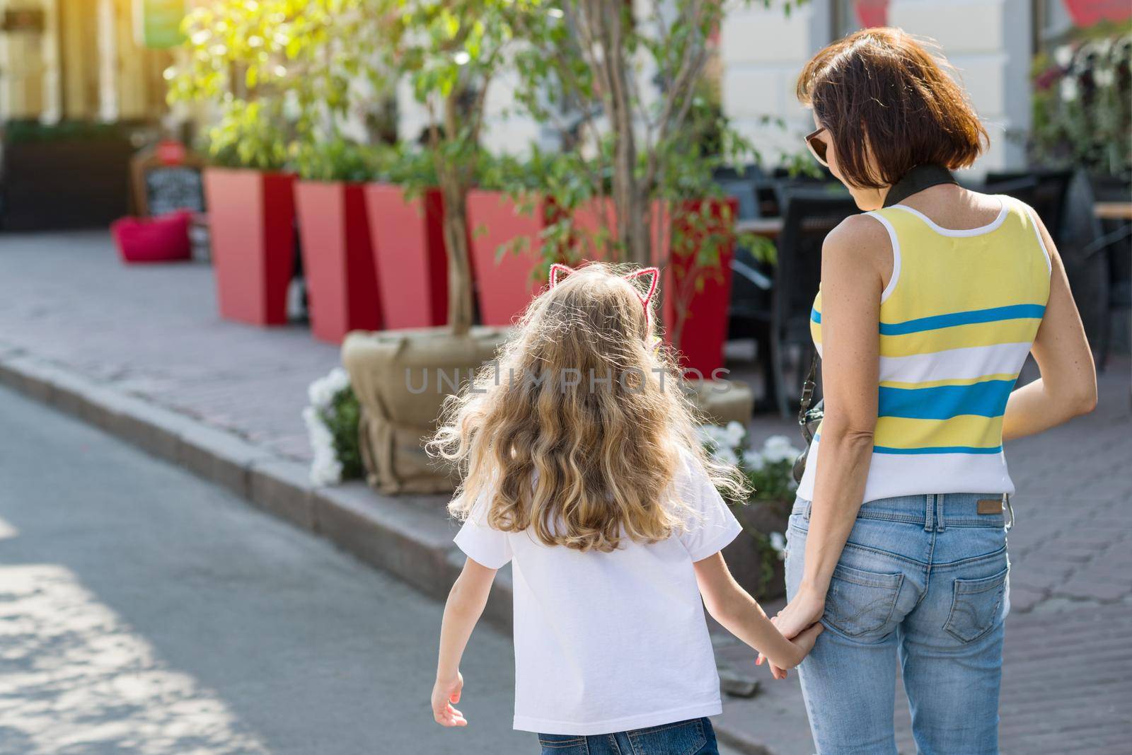 Urban portrait of mother and daughter. Back view.