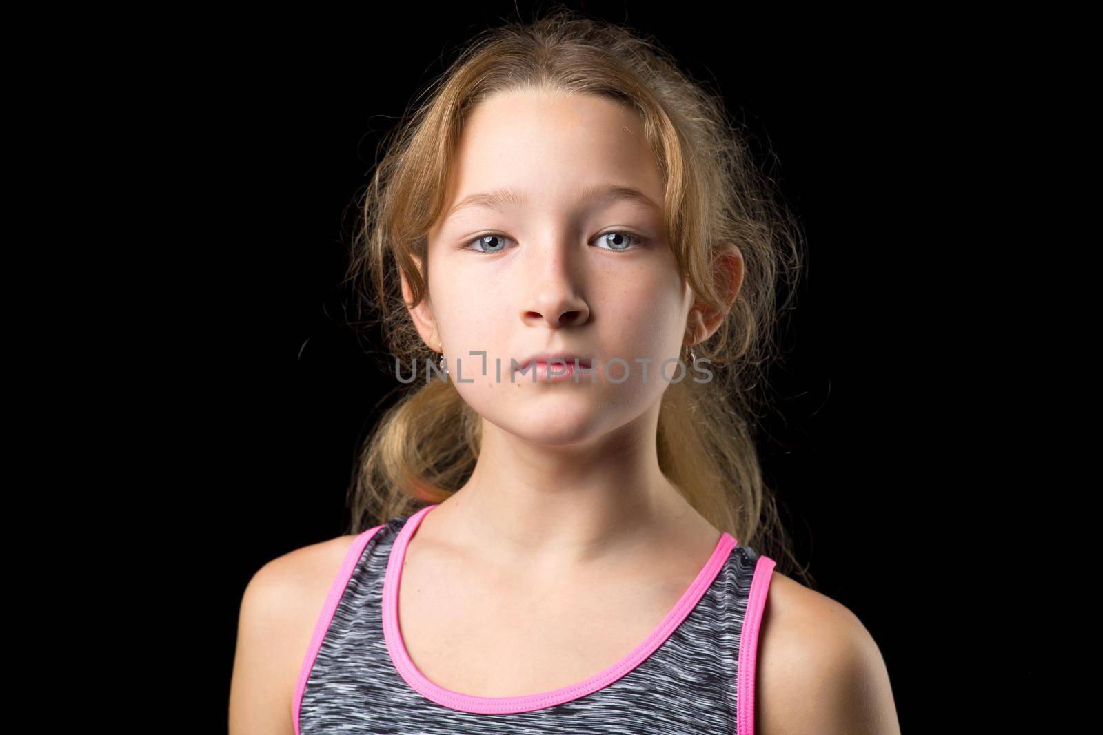 Portrait of a cute sporty teenage girl. Pretty girl wearing tracksuit posing on black background. Happy childhood concept