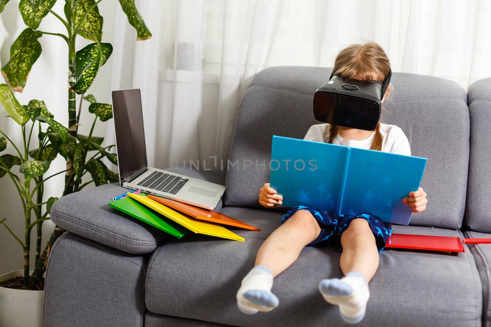 Trying new technologies. Little schoolgirl wearing big VR glasses being impressed playing virtual games. Home school, online education, home education, quarantine concept - Image by Andelov13