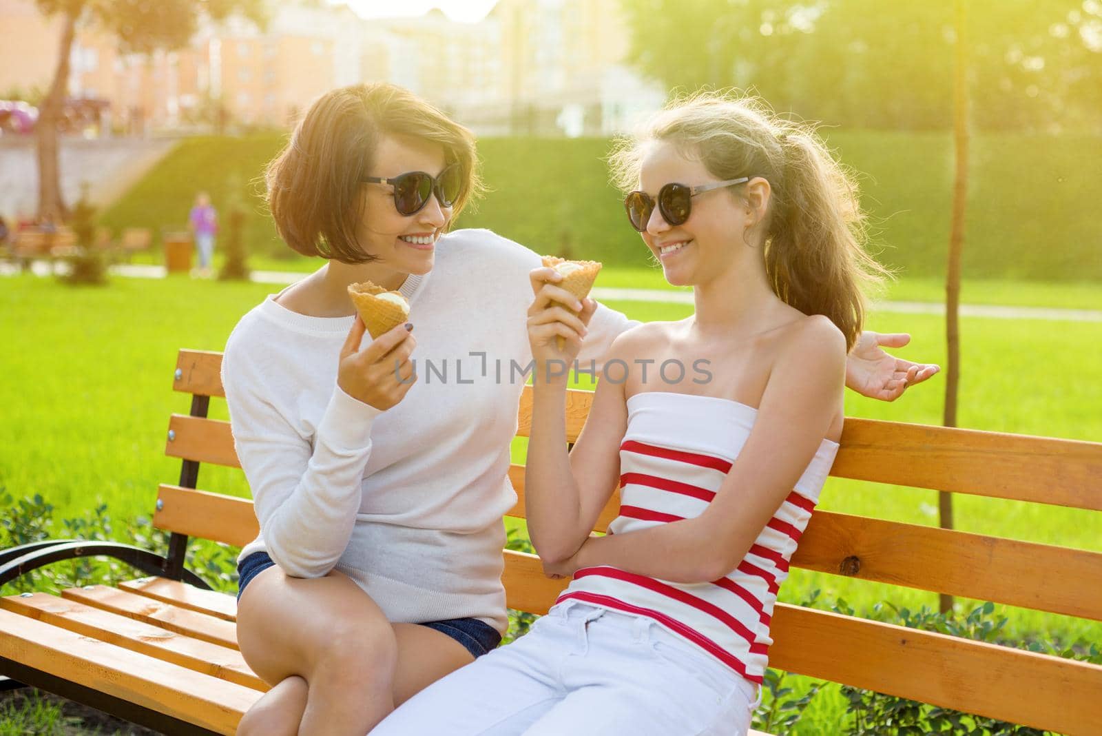Mom and daughter laugh, eat ice cream and enjoy socializing.