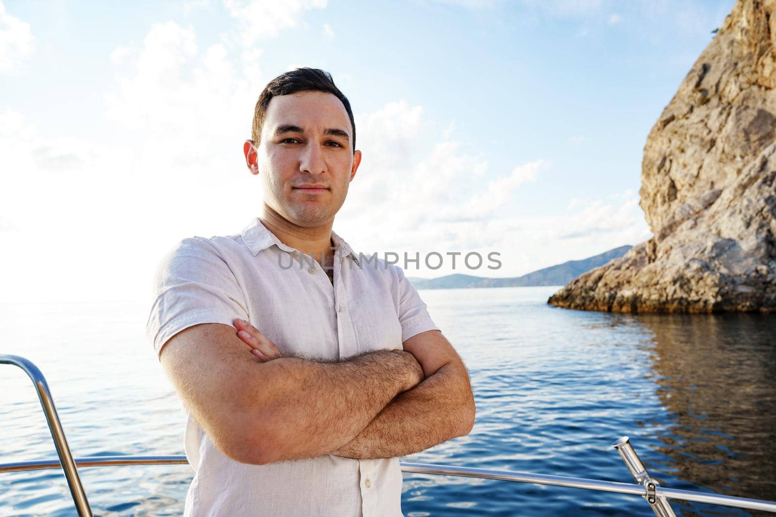 Young man in white shirt standing on the nose yacht in the sea by Fabrikasimf
