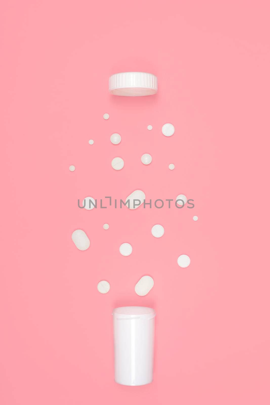 Medical background with pills. White pills pour out of a bottle on a pink background. Flat lay concept.