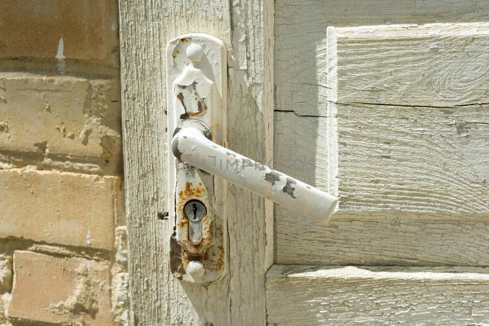 Detail of white vintage wooden door with a painted cracked door handle.