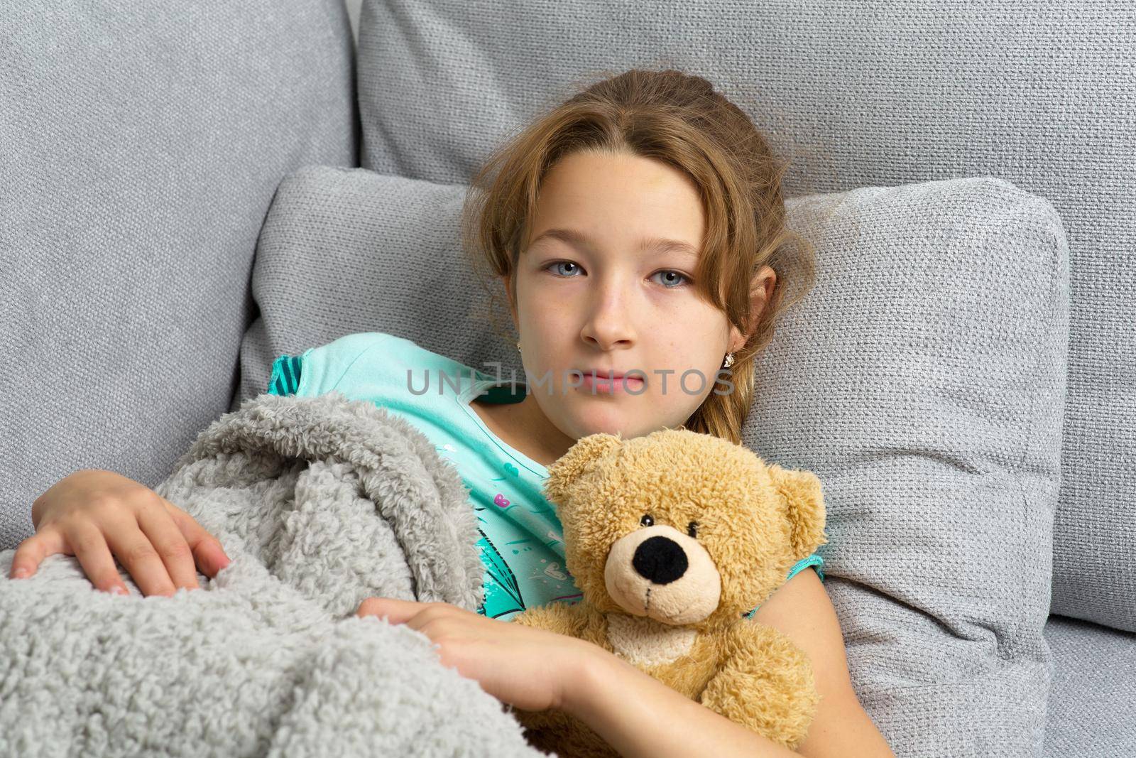 Girl lying on sofa with fluffy teddy bear by kolesnikov_studio