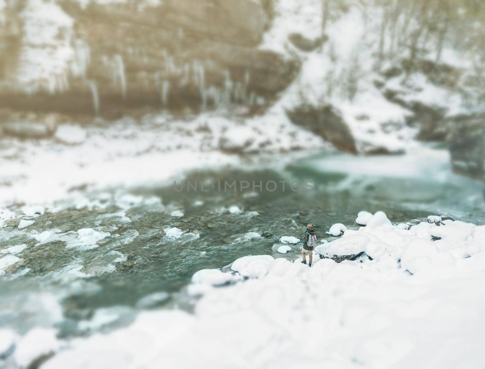 Traveler woman walking along the river bank in winter, image with tilt-shift effect.