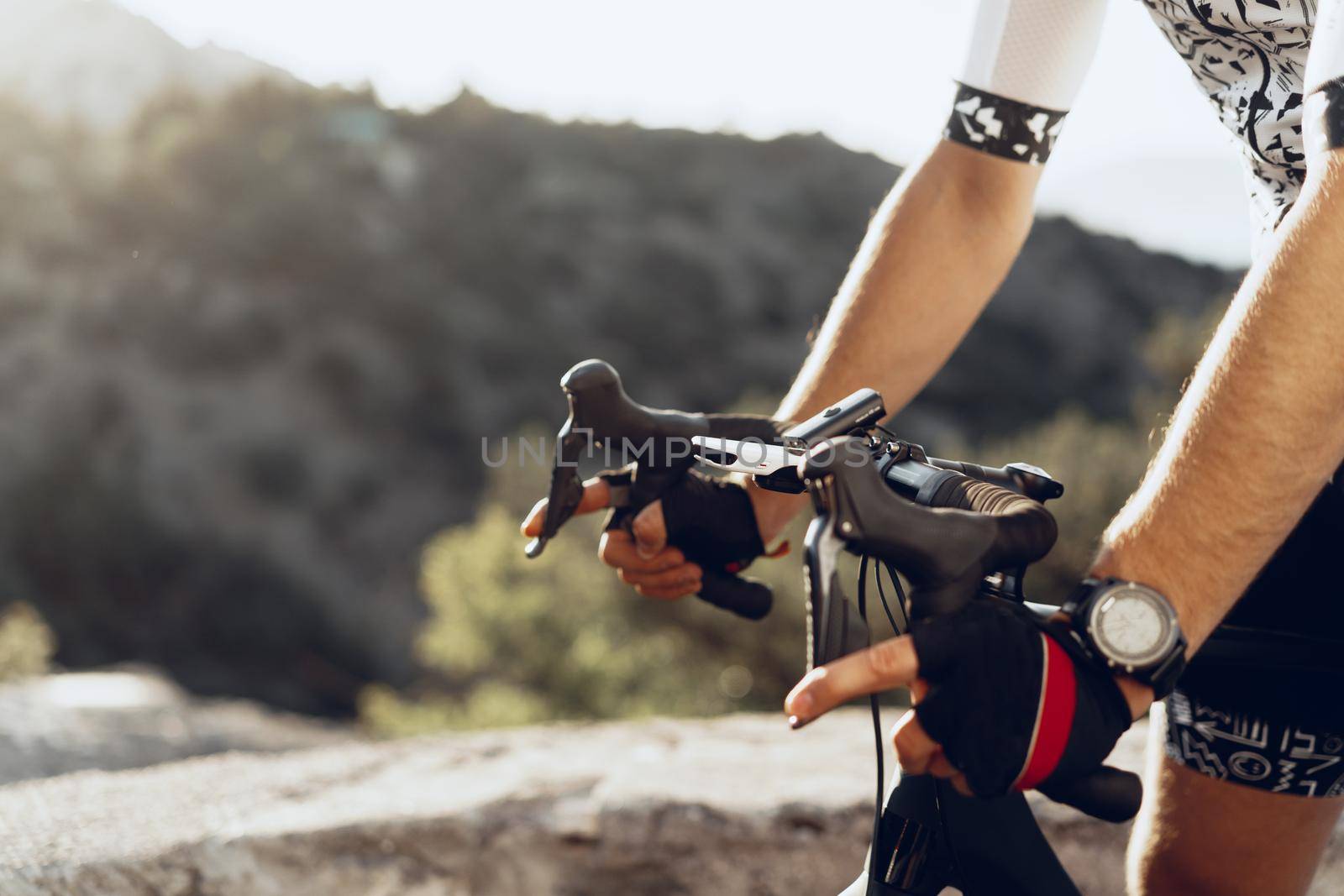 Hands of a professional cyclist in gloves on handle bar of a bicycle close up