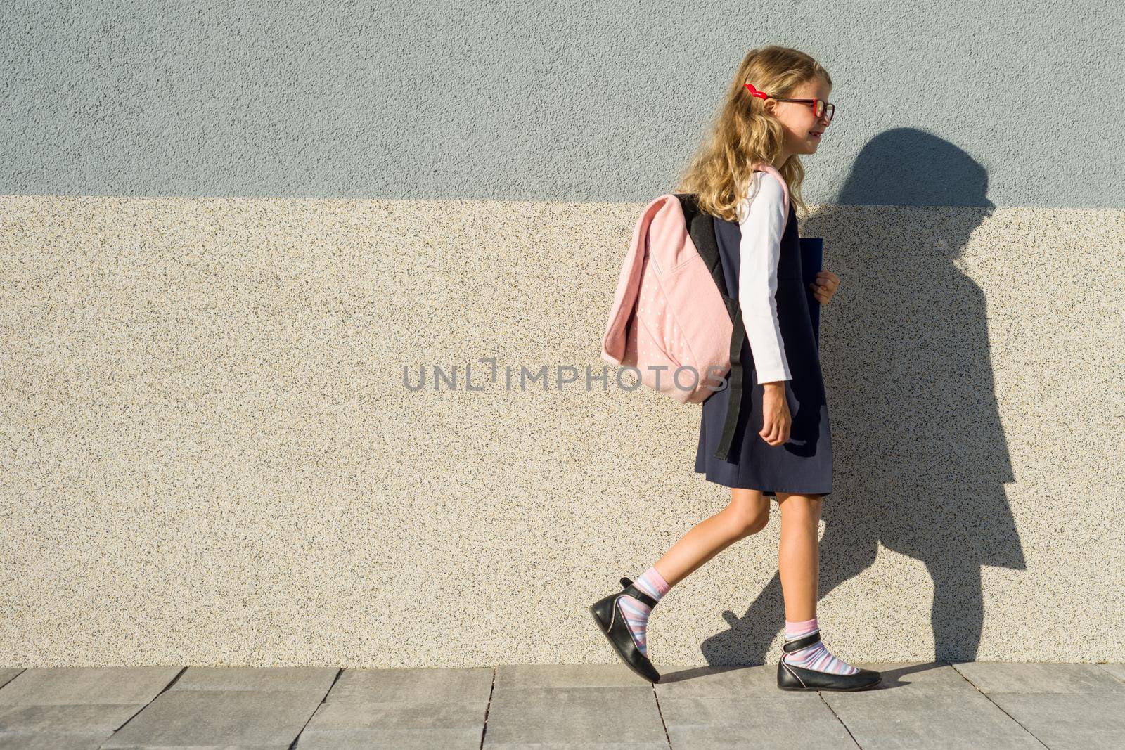 A schoolgirl of elementary school with notebooks in his hand. A girl with a backpack goes to school. Back to school