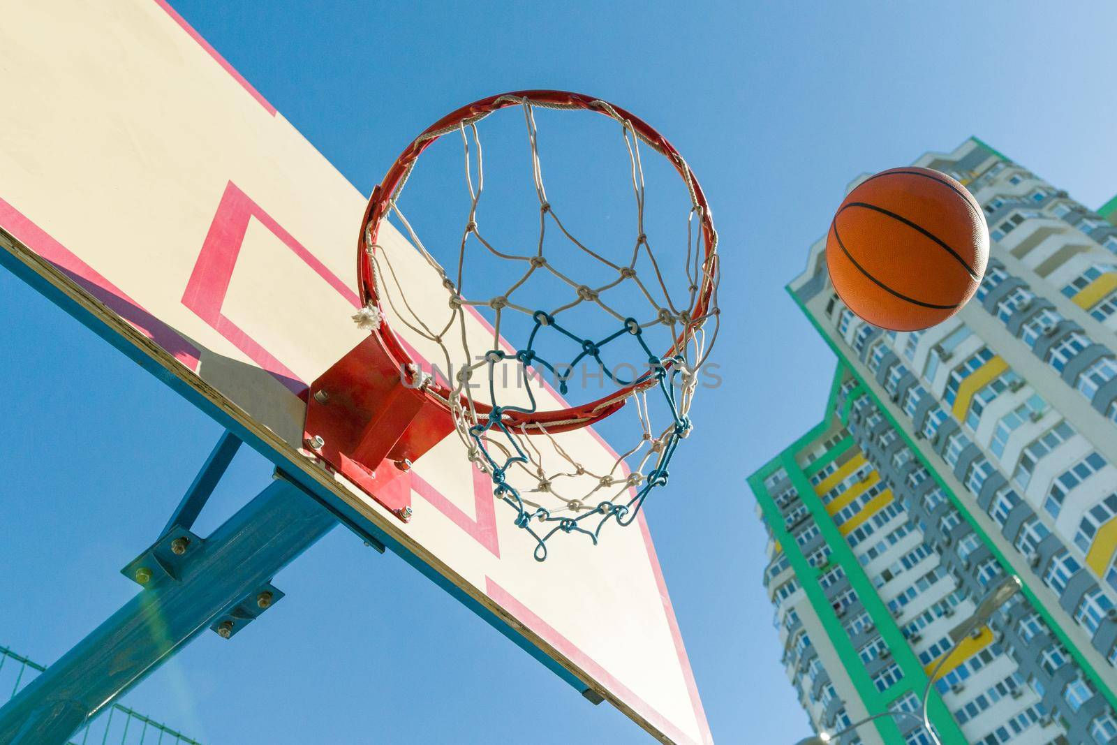 Street basketball, close-up of basketball ring and ball flying into the basket. by VH-studio