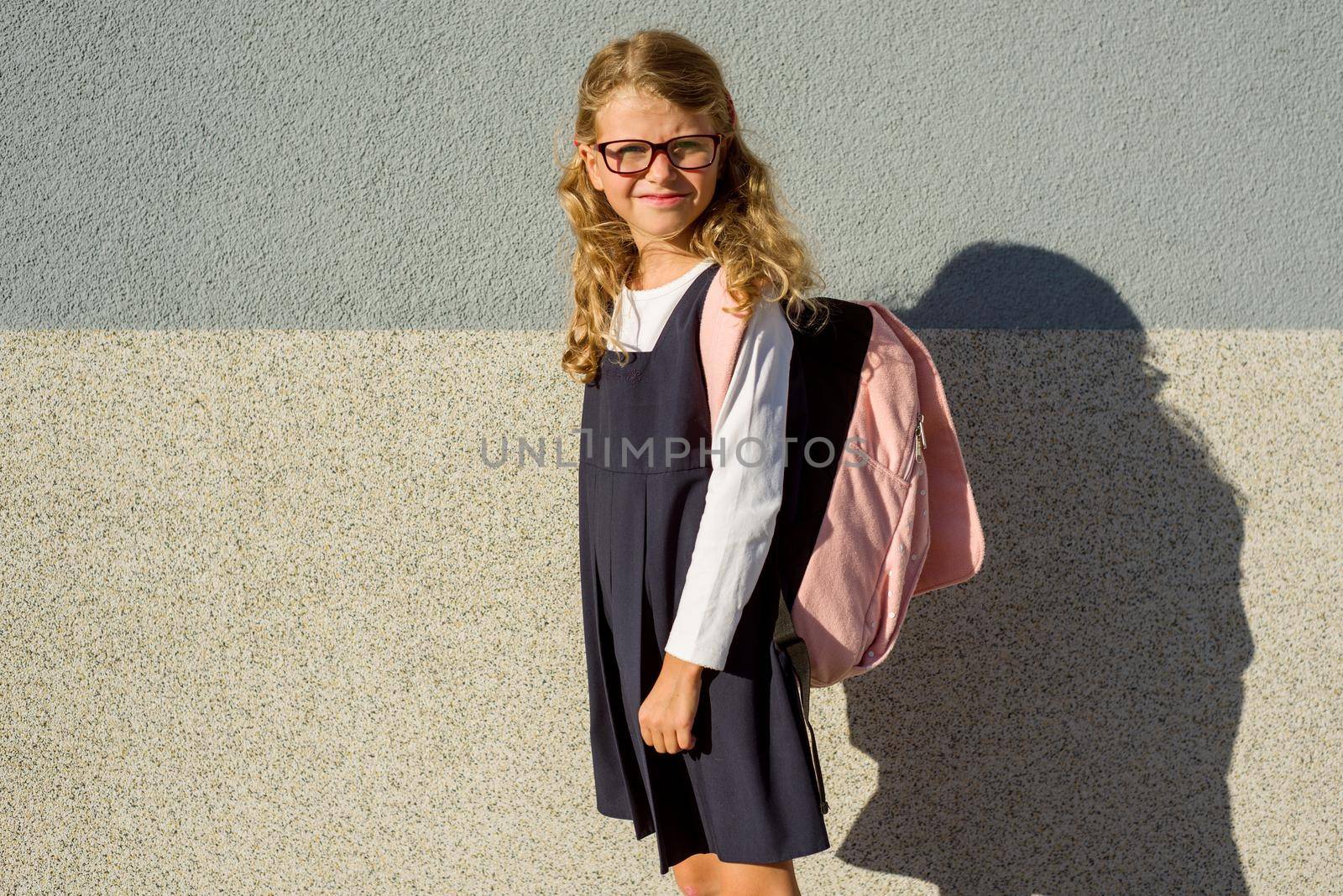 Outdoor portrait of an elementary school student in uniform with schoolbag. by VH-studio