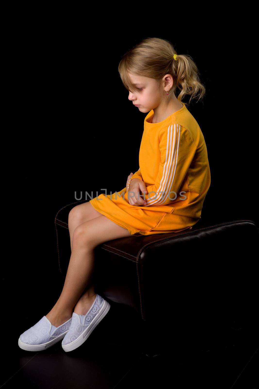 Beautiful studio portrait of a little girl in profile. On a black background.