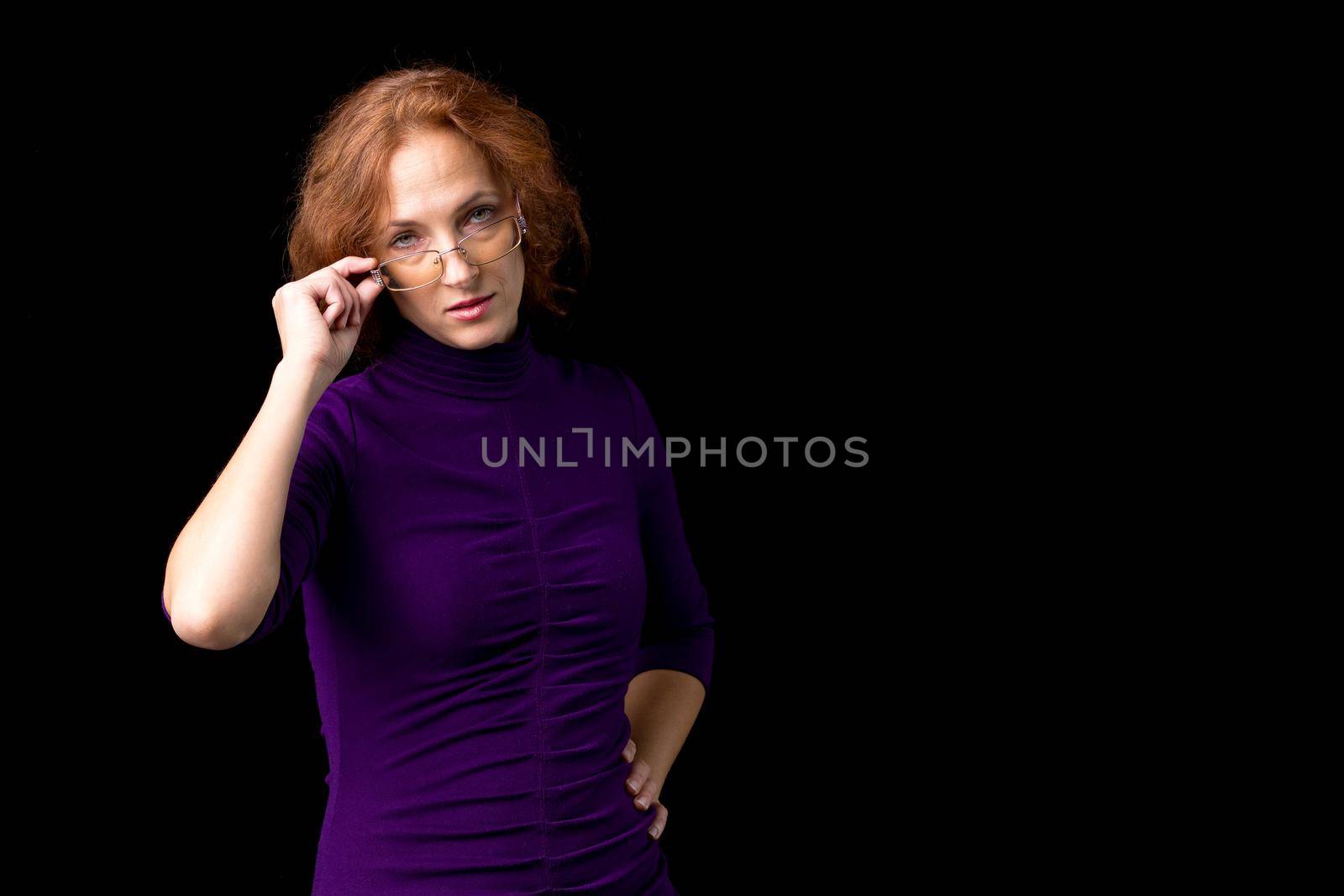 Young woman looking strictly over her glasses. Woman teacher wearing glasses and purple casual dress looking angrily. Female person posing against with background with copy space for text or design