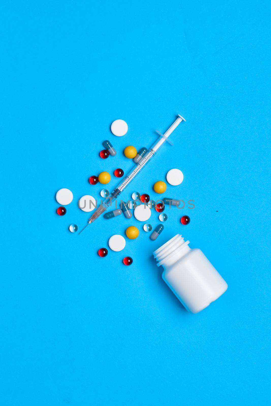 multicolored pills Pharmaceuticals medicines syringe blue background by Vichizh