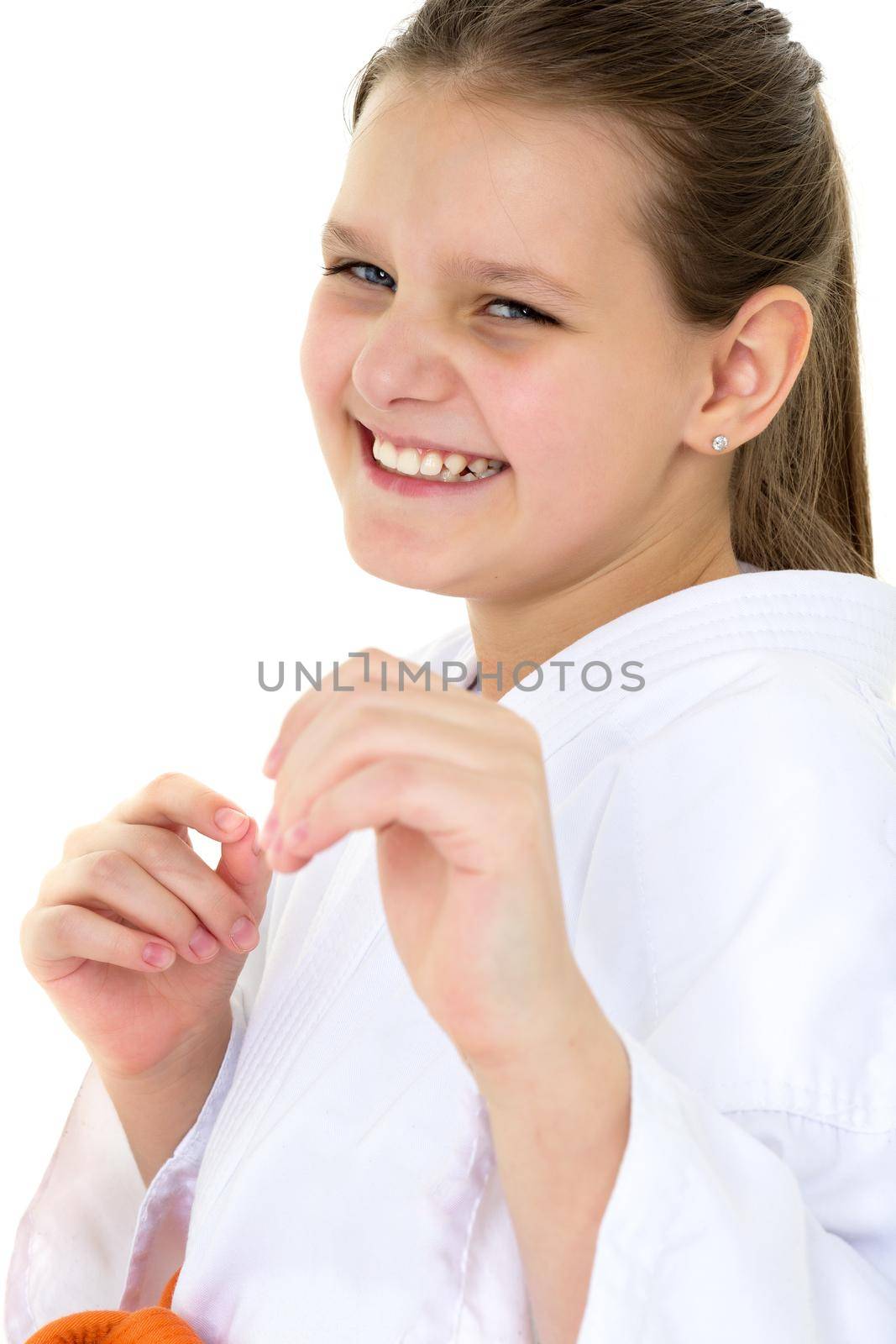 Portrait of happy girl training in kimono. Smiling cute karate girl dressed sportswear posing in fighting stance on isolated white background. Healthy lifestyle, sport and fitness concept