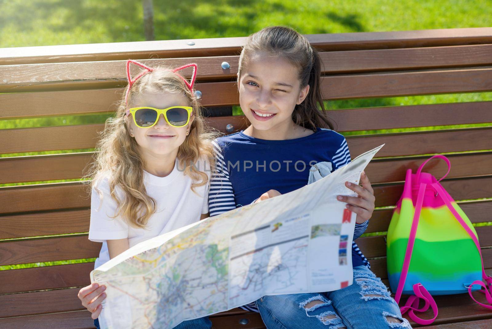 Outdoors portrait children tourists. With map of city on the bench.