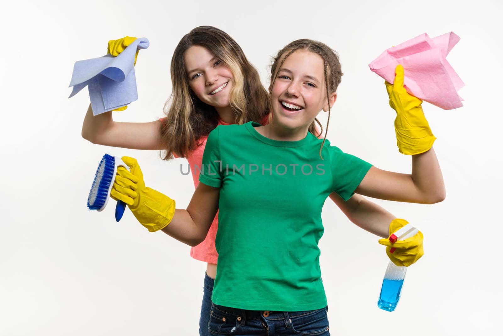 Cleaning, domestic duties and teamwork concept. Two teenage sisters wearing yellow protective gloves and holding them for cleaning by VH-studio