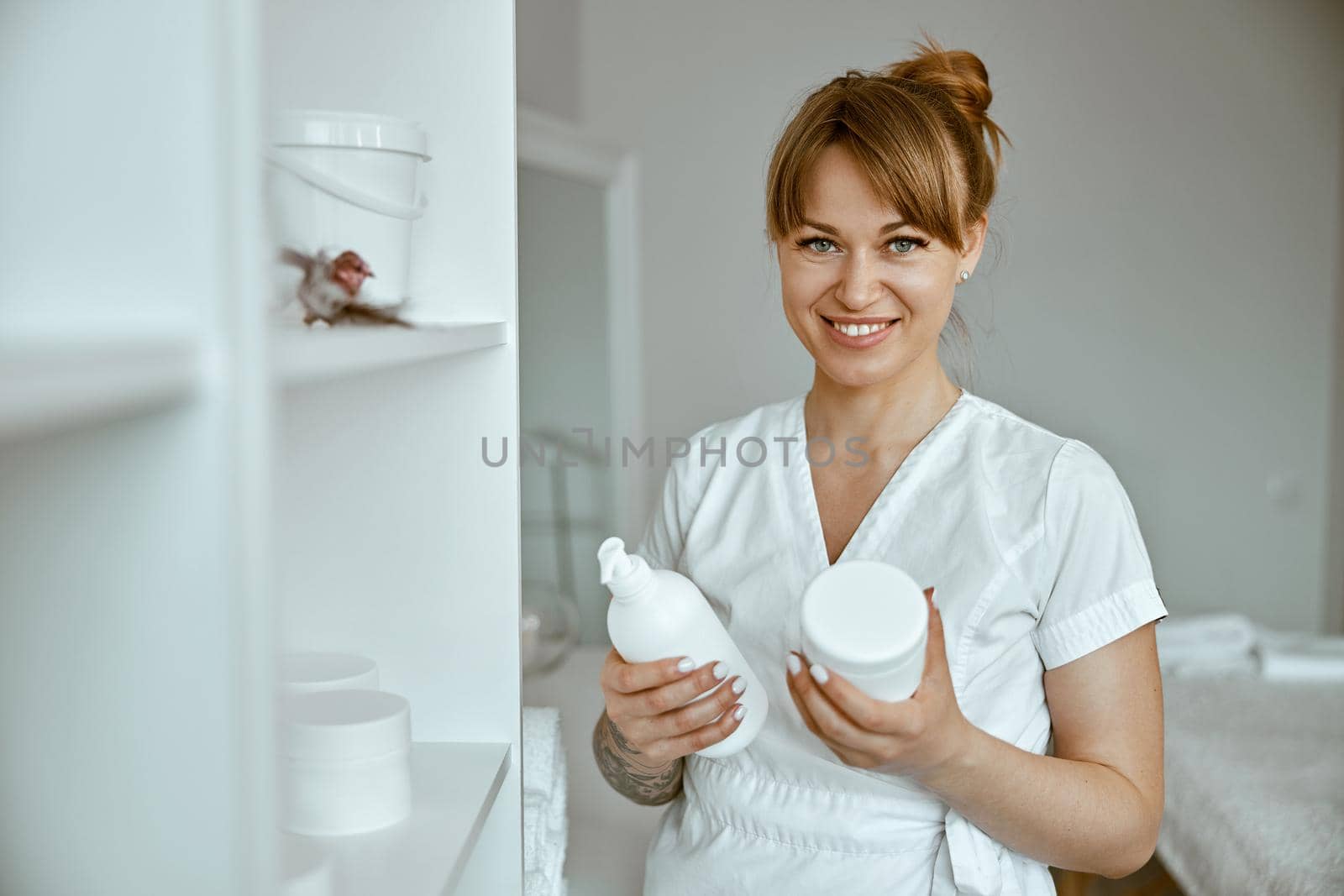 beautiful happy caucasian female masseur is posing in white minimalistic modern treatment salon