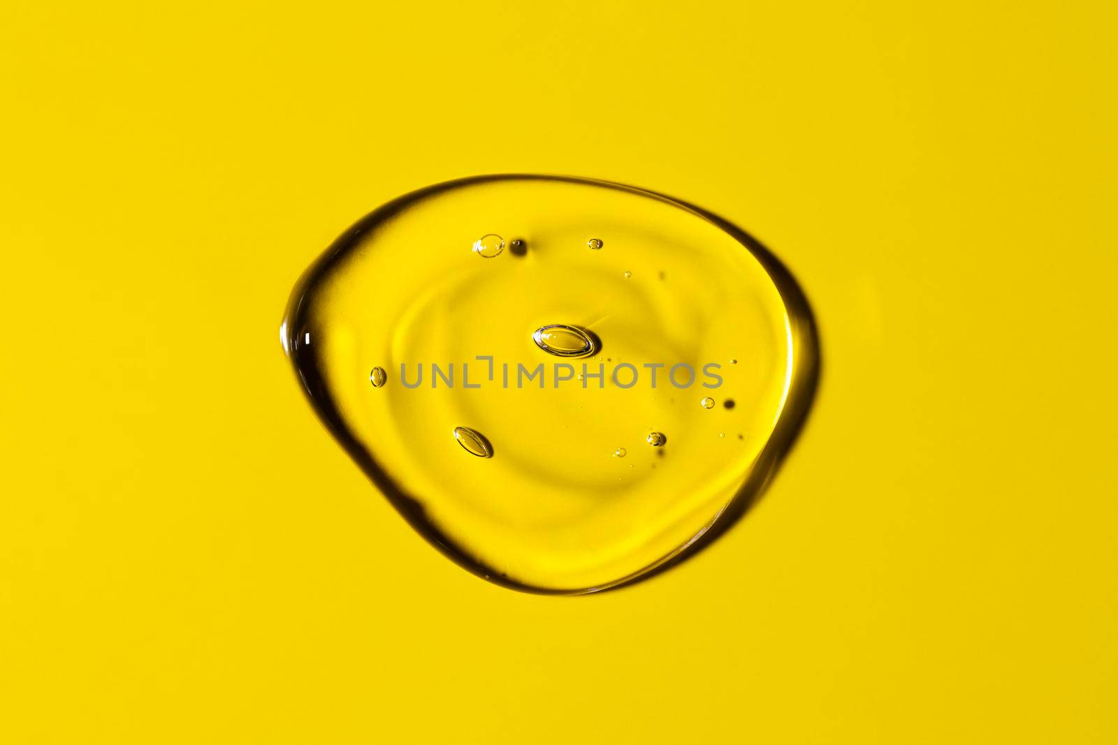 Clear transparent round liquid gel drop or smear isolated on yellow background. Top view. Virus protection or cosmetics concept. Serum texture