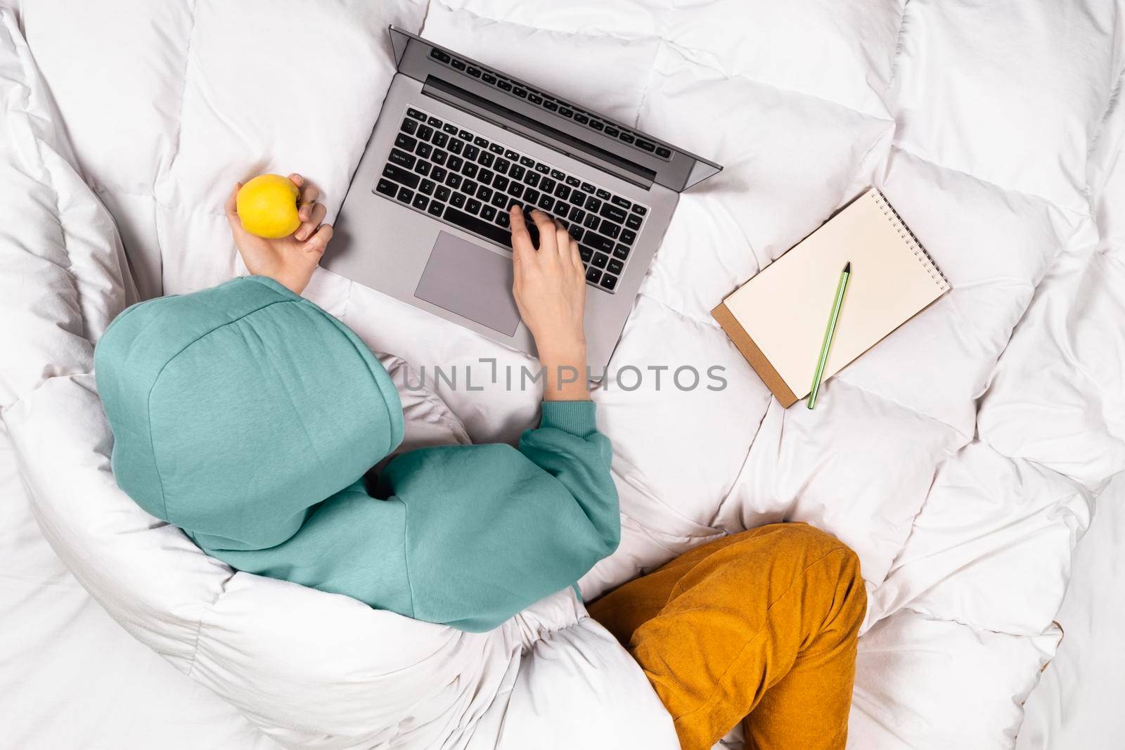 Top view on girl working on modern laptop from bed at home . Home office or online education concept. Cozy home concept banner by esvetleishaya