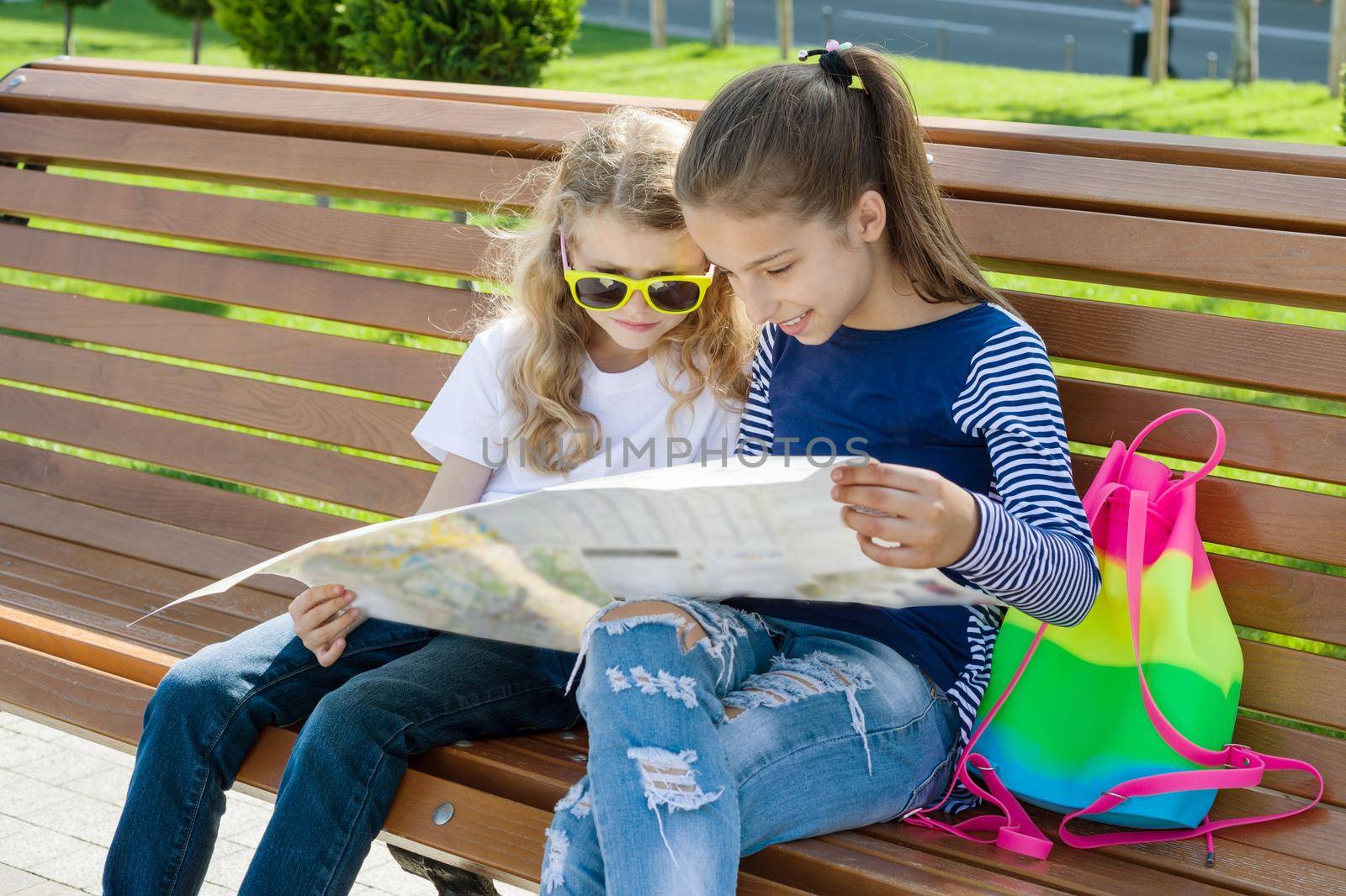 Outdoors portrait children tourists. With map of city on the bench by VH-studio