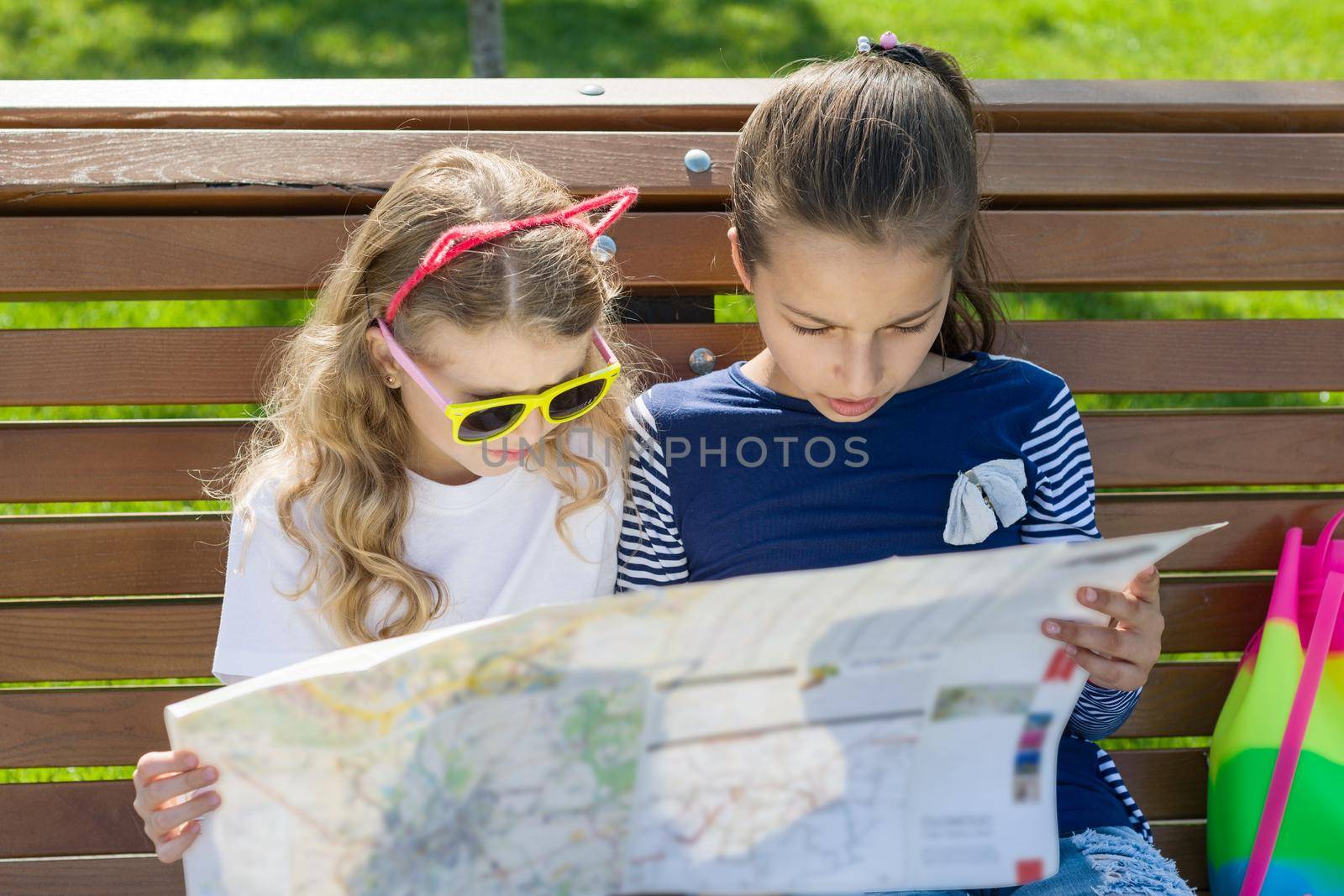 Outdoors portrait children tourists. With map of city on the bench by VH-studio