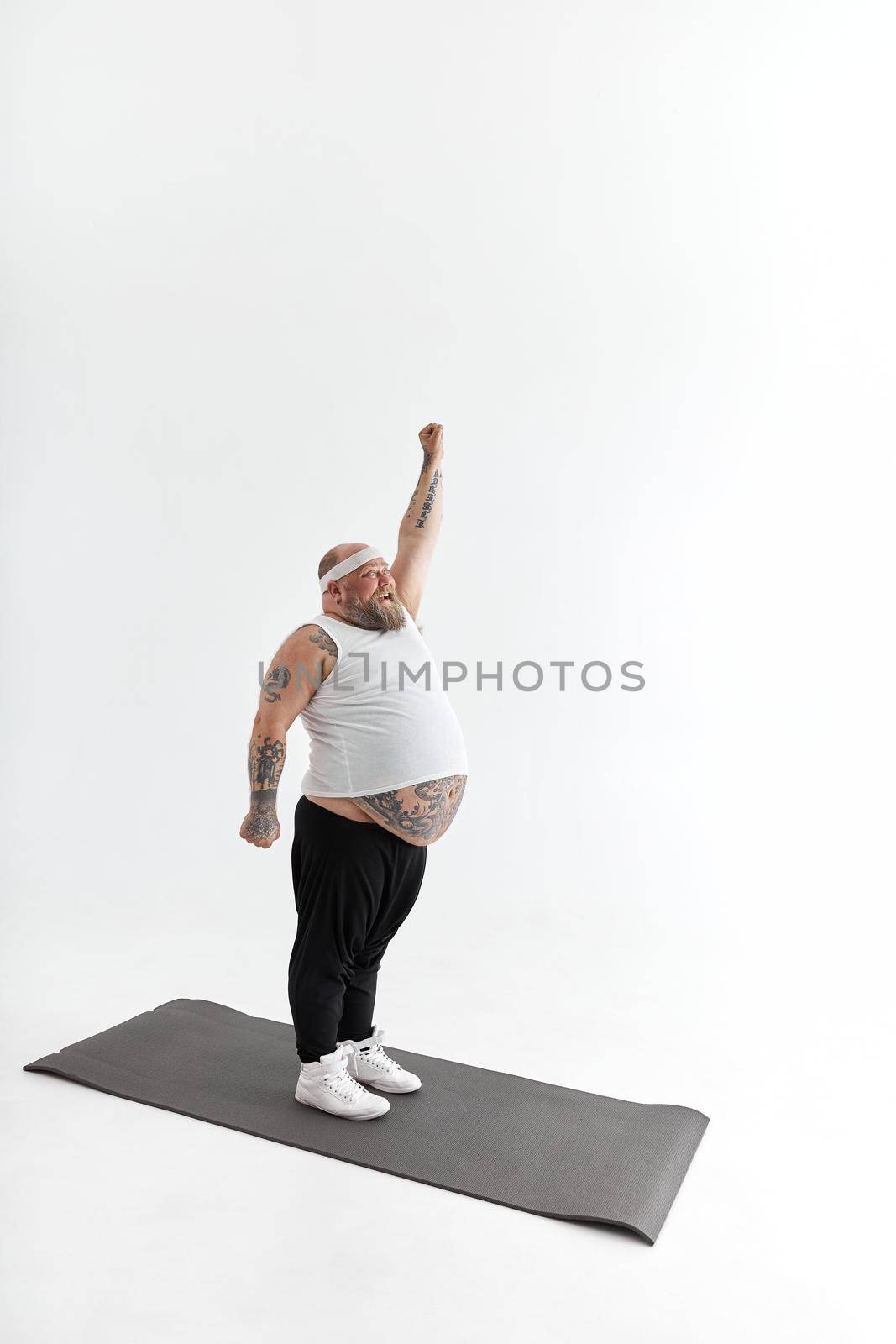 Sporty fat man with beard and tattoos is doing yoga