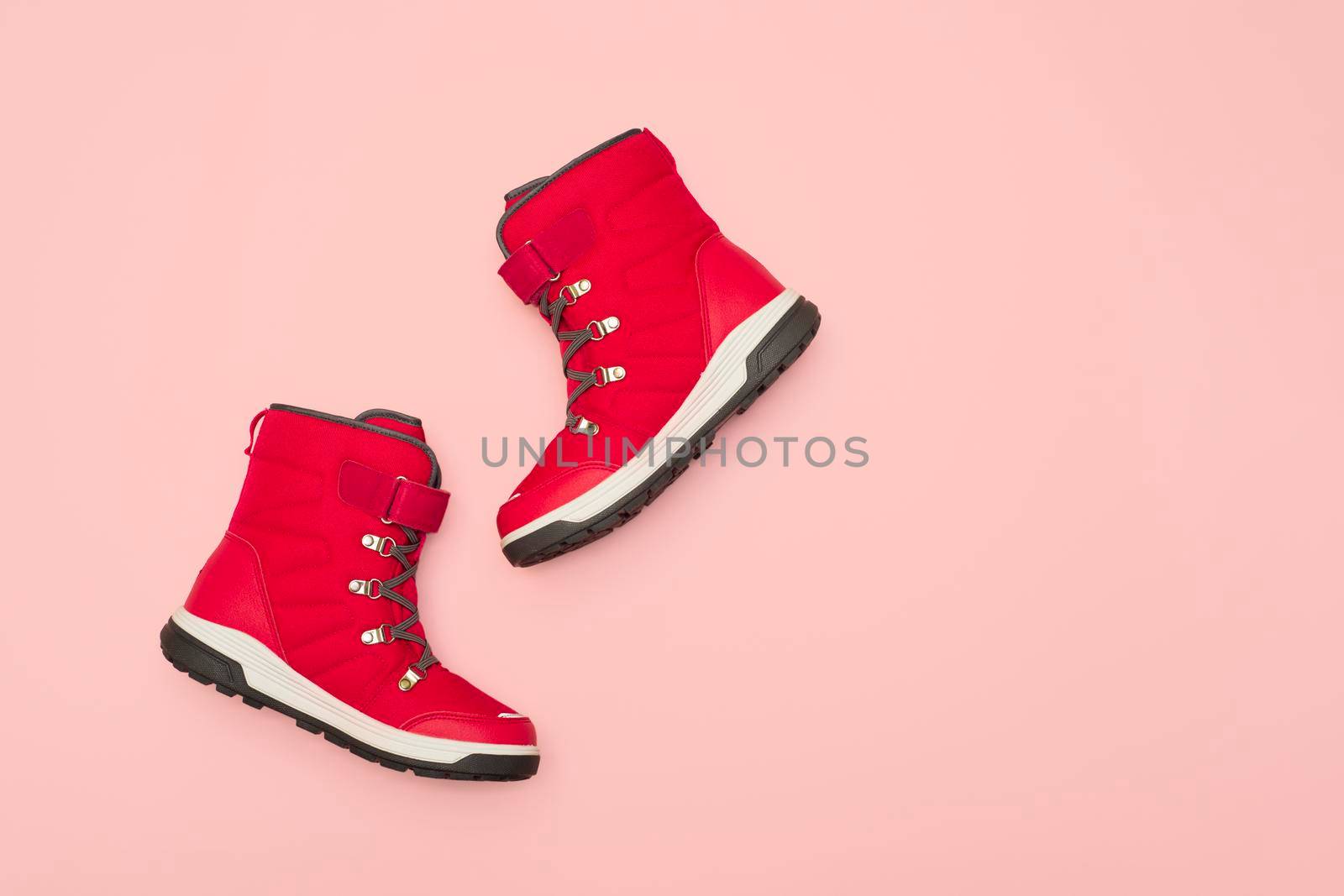 Kids or teenage pink winter boots isolated on pink background. Winter boots for girls