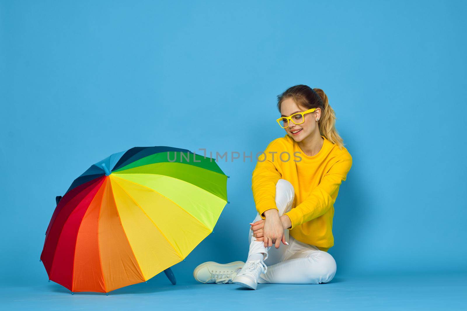 woman with multicolored umbrella in yellow sweater posing rainbow colors. High quality photo