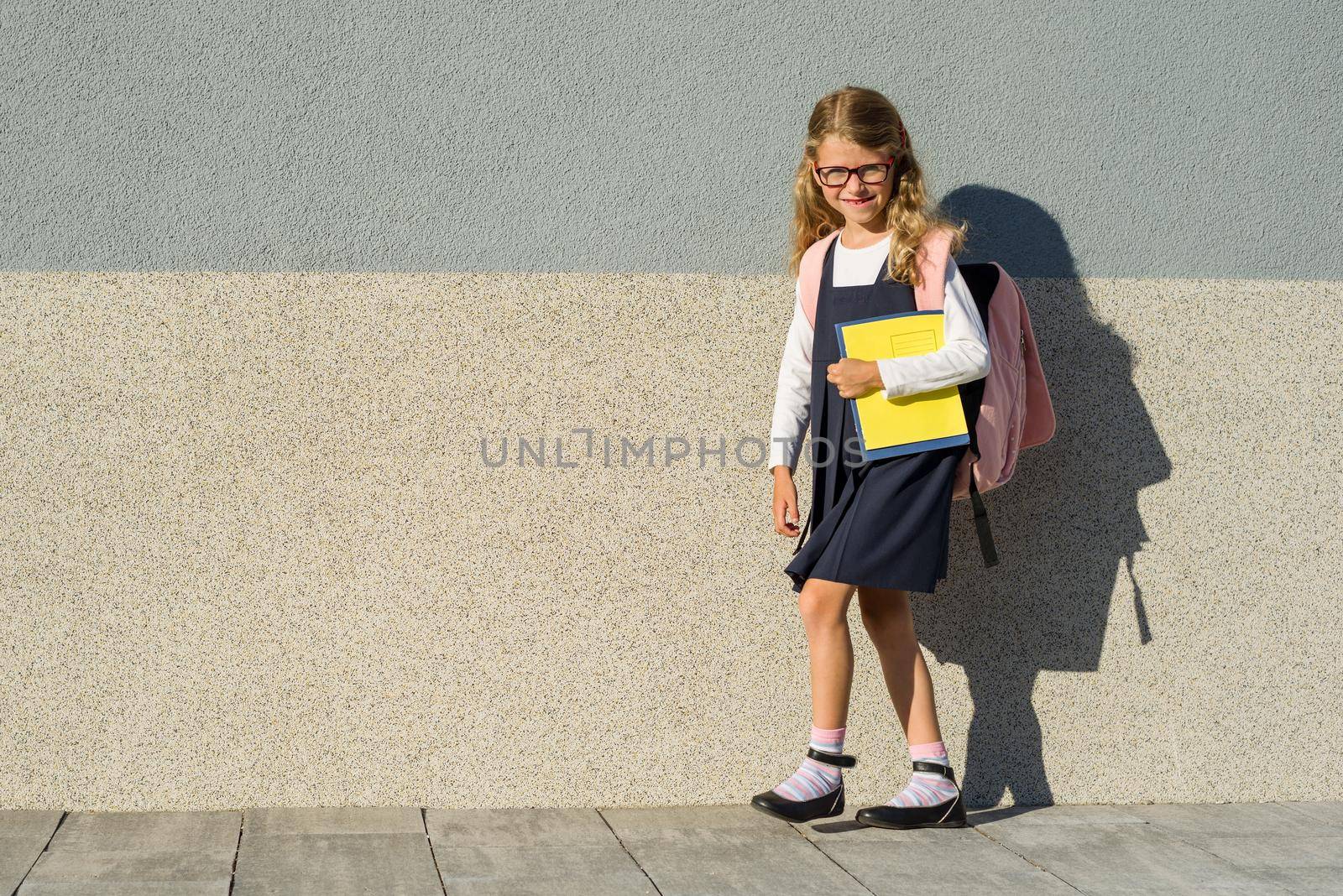 Schoolgirl with notebooks in hand. A girl with a backpack goes to school. Back to school!