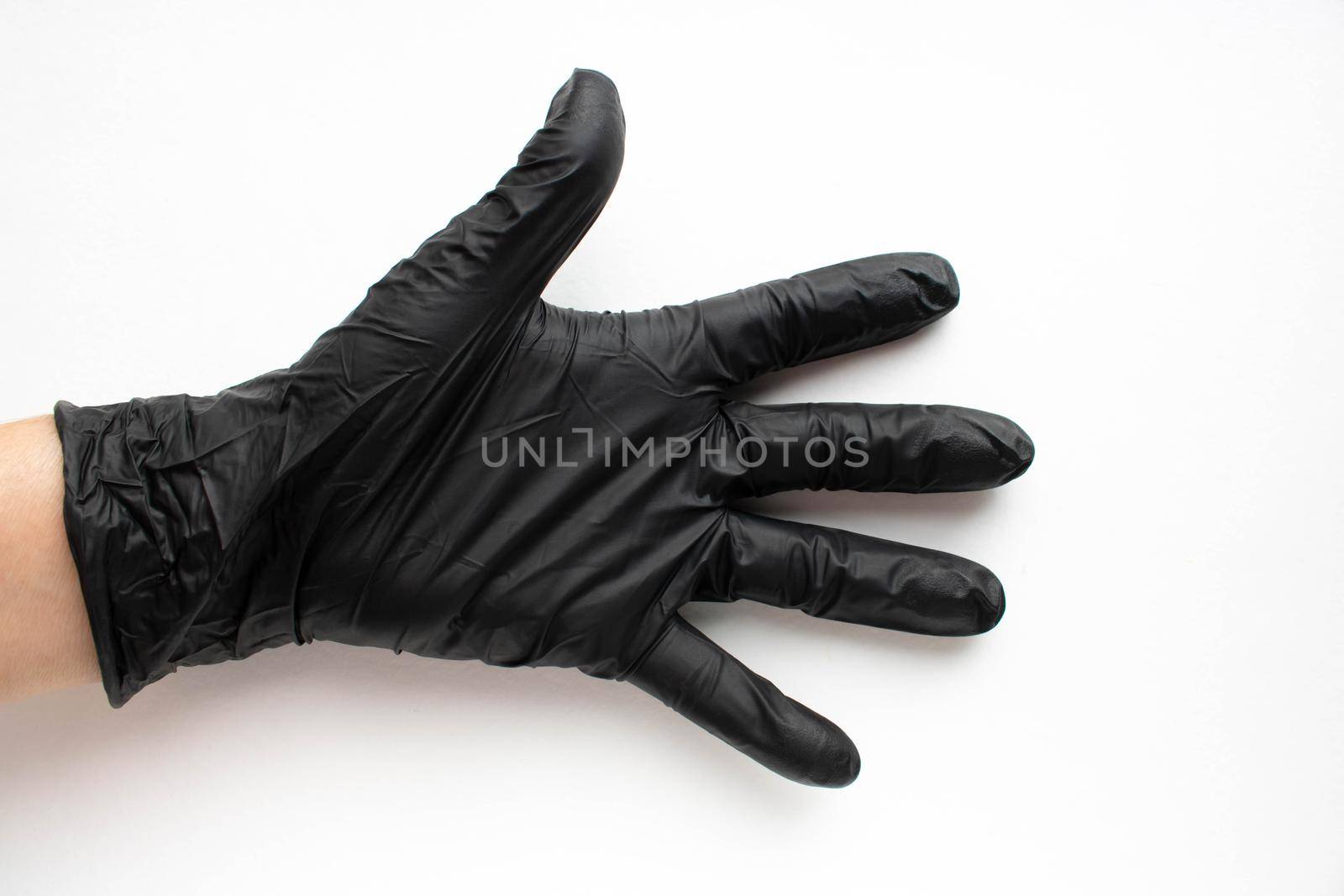 Hand in a black surgical medical glove, isolated on a white background. Production of rubber protective gloves.Hygiene and sanitary standards.