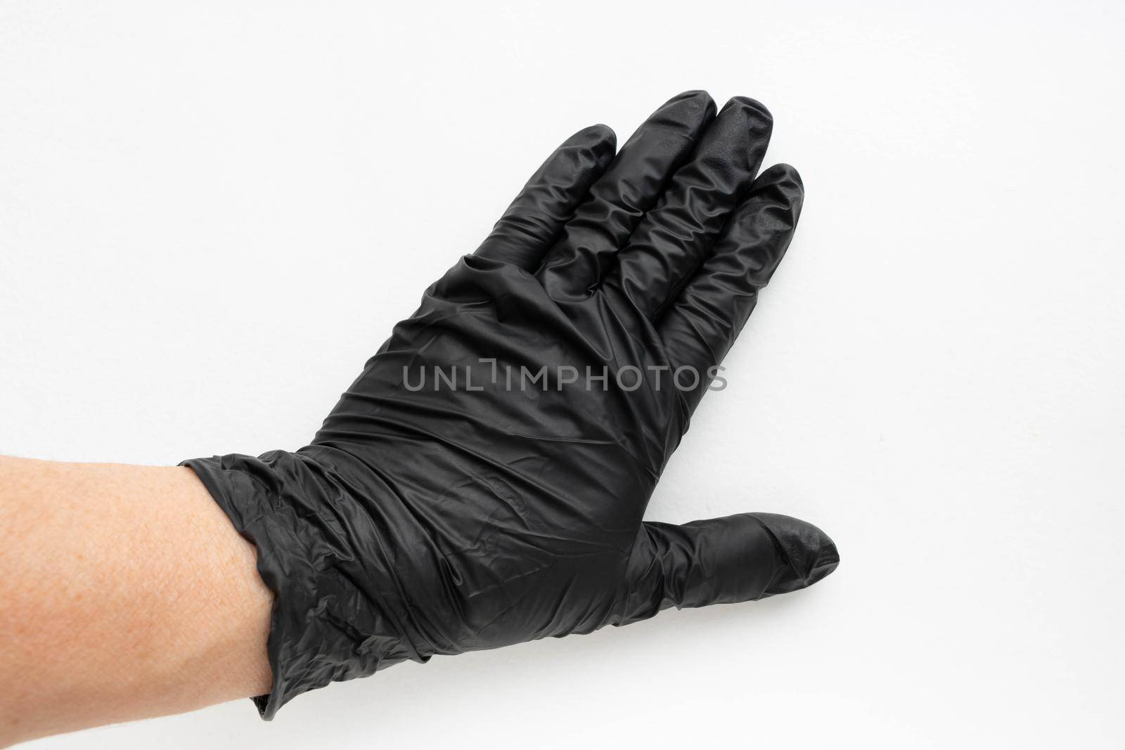 Hand in a black surgical medical glove, isolated on a white background. Production of rubber protective gloves.Hygiene and sanitary standards.