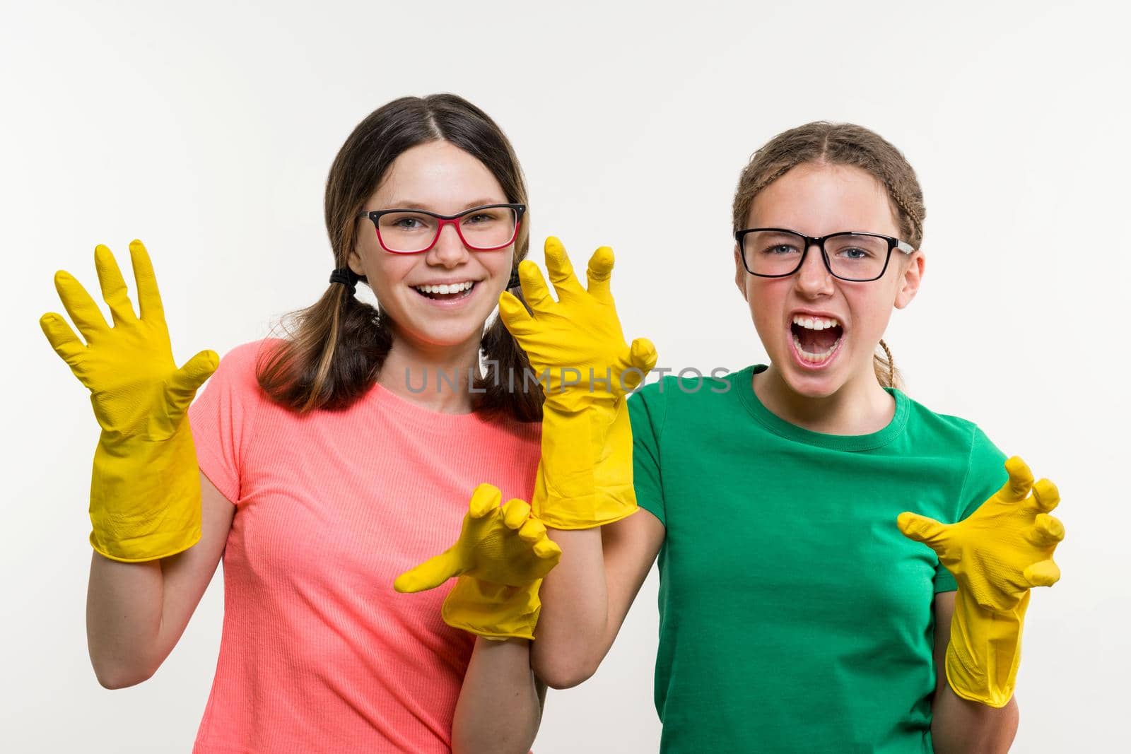 Cleaning, domestic duties and teamwork concept. Two teenage sisters wearing yellow protective gloves.