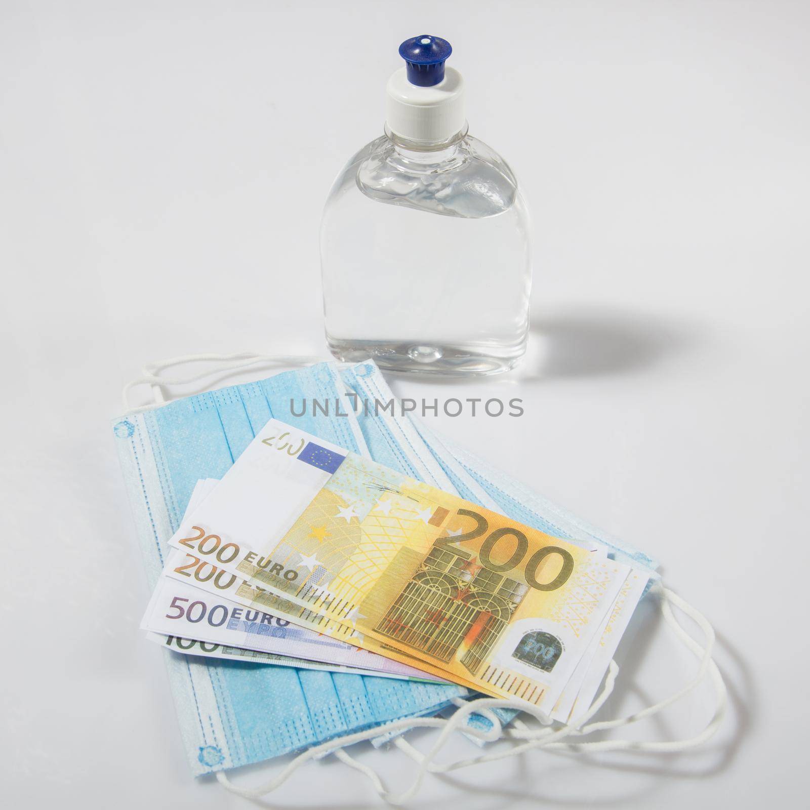 Alcohol gel hand sanitizer and disposable hygienic mask and euro banknotes on gray background