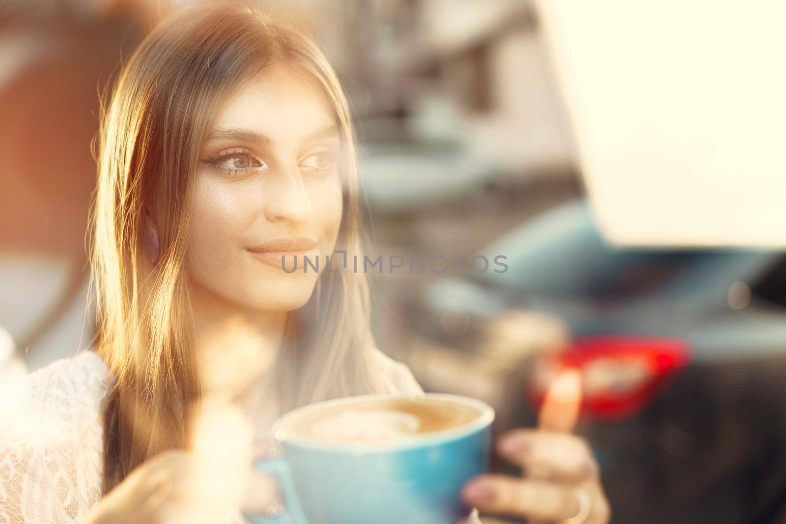 Portrait of a young woman having a cup of coffee and looking through the window. Close up.