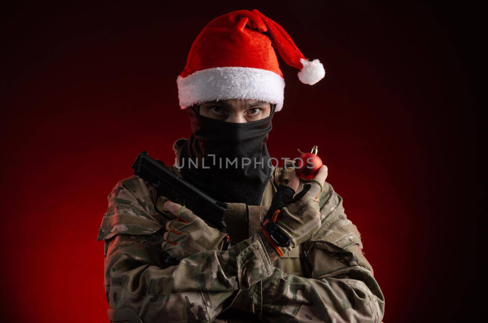 the man in a military uniform with a gun and a Santa Claus hat