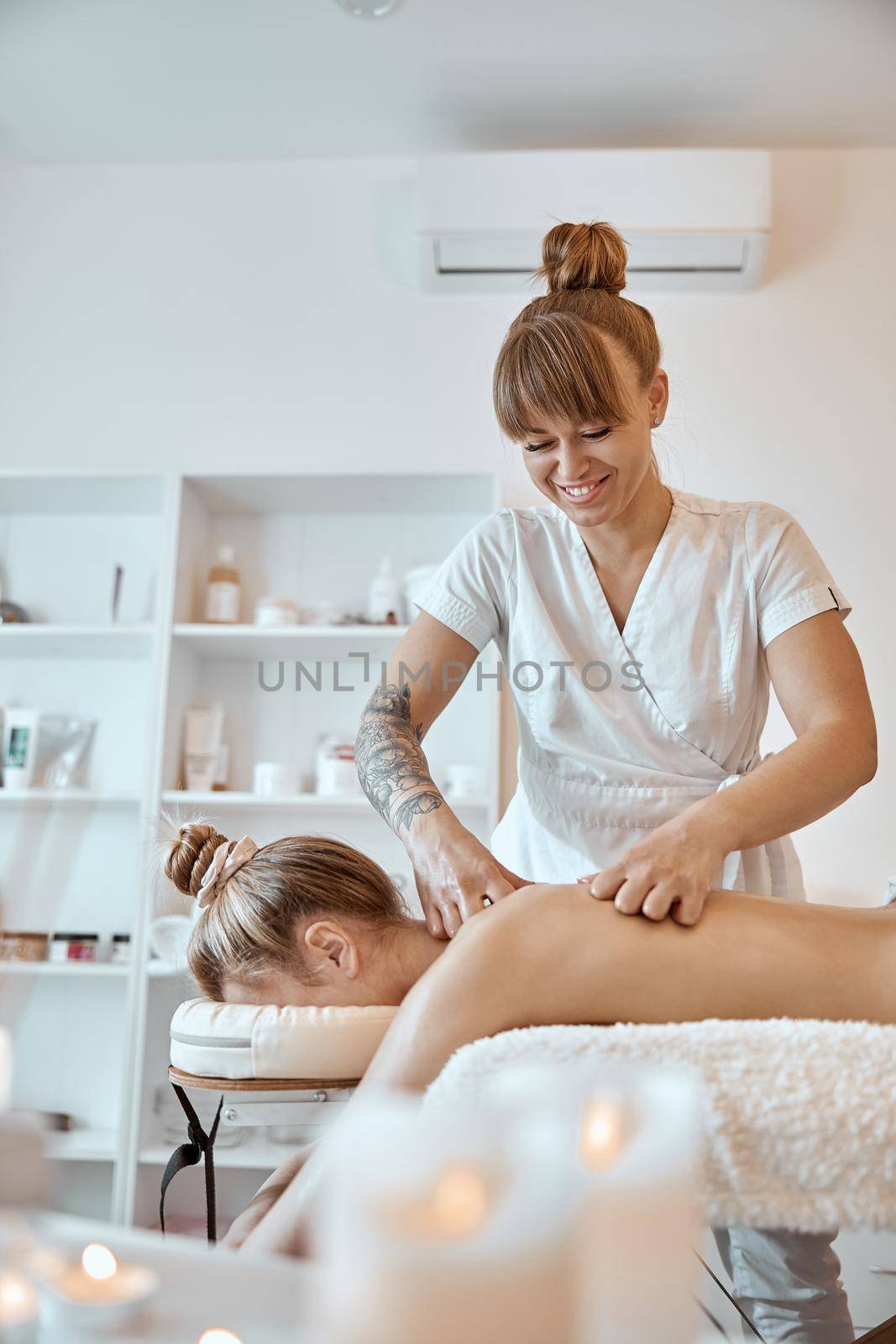 Professional confident massage master is doing procedures to caucasian woman in minimalistic modern cabinet