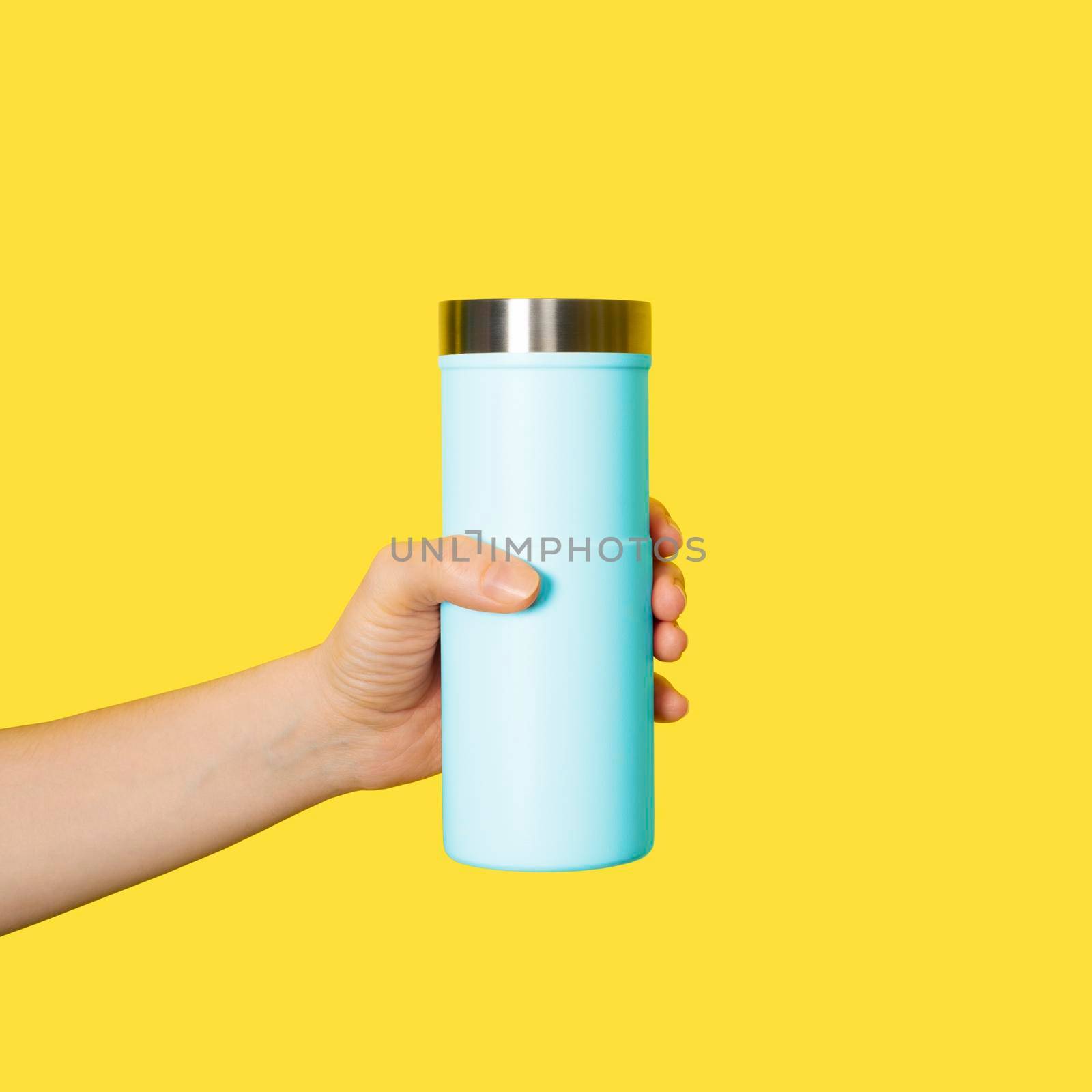 Hand holds travel mug isolated on white background. Thermo cup or tumbler in female hand by esvetleishaya
