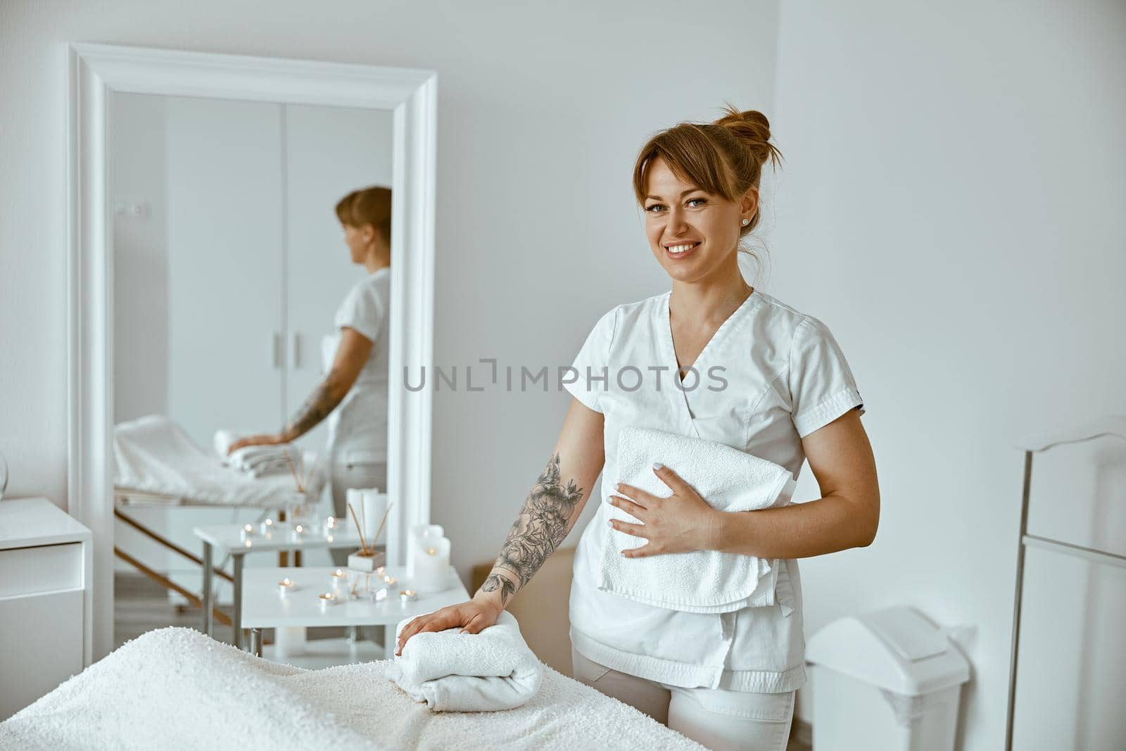 beautiful happy caucasian female masseur is posing in white minimalistic modern treatment salon