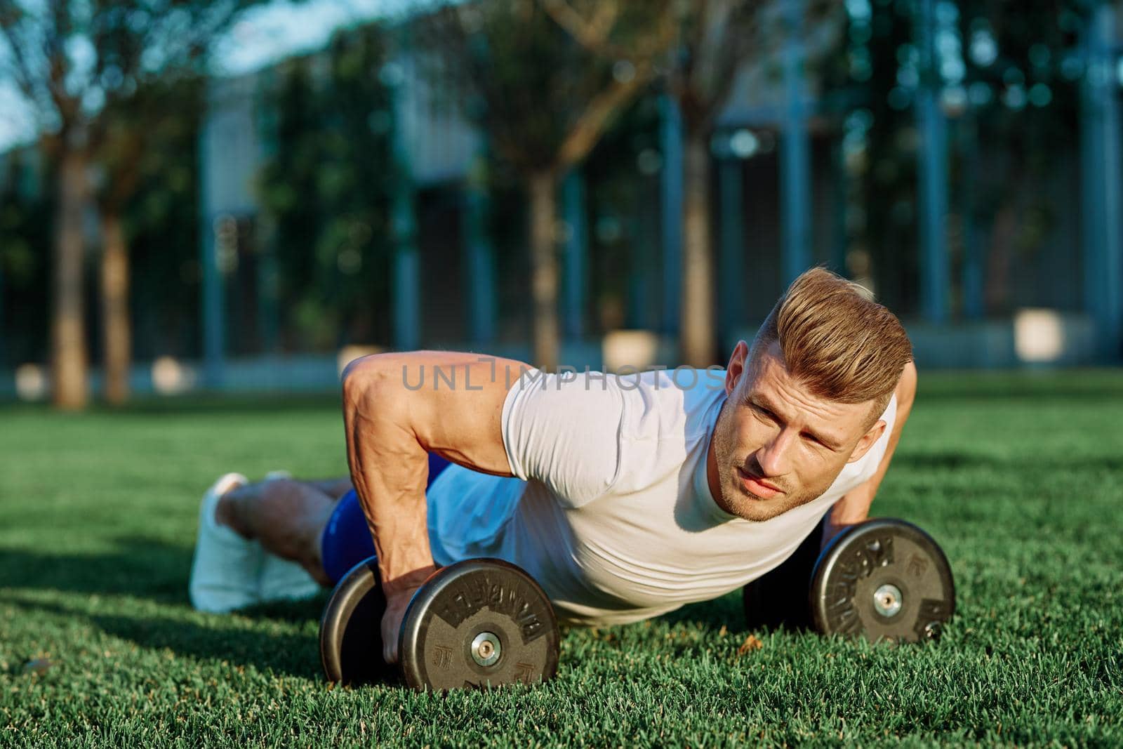 athletic man training with dumbbells in the morning Park. High quality photo