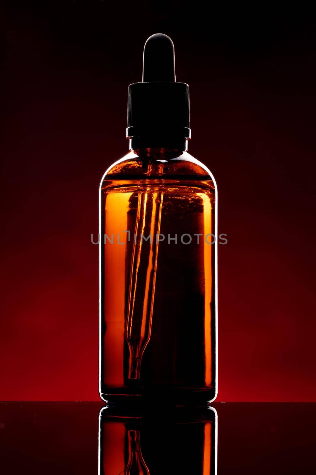 Glass bottle with cosmetic oil on dark background by Fabrikasimf
