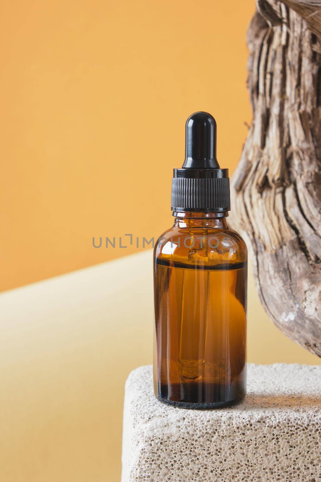 brown glass bottle with a pipette on a concrete podium on a wooden driftwood background, brown background copy space natural cosmetic concept