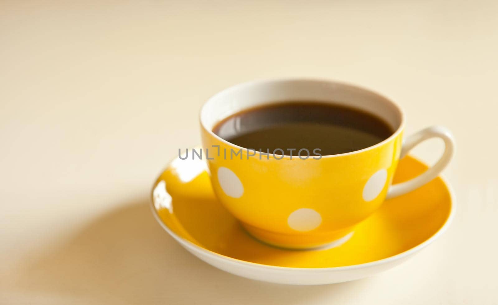 cup of black tea on yellow plate. yellow cup with dots. retro style. vintage yellow mug