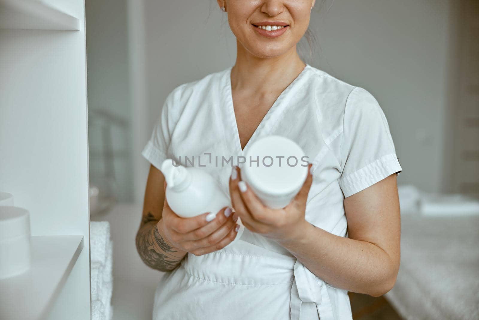 beautiful happy caucasian female masseur is posing in white minimalistic modern treatment salon