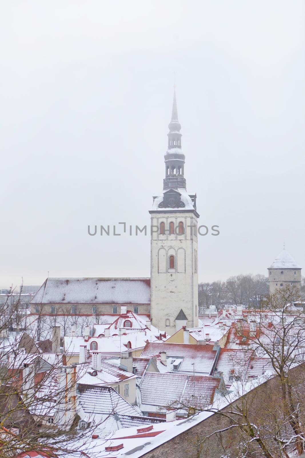 Old town of Tallinn, Estonia. Vertical photo of St. Nicholas Church, Niguliste facade. Snow and roofs of old town at winter time