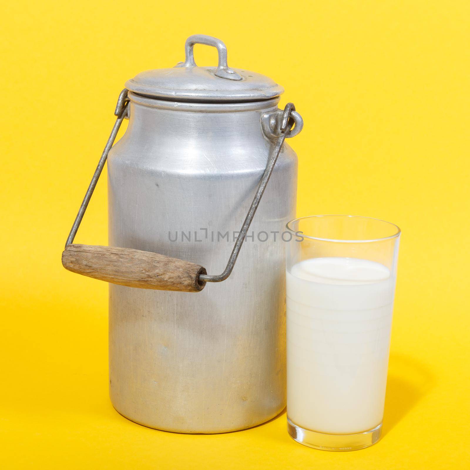Old Milk Canister and glass of milk on yellow background
