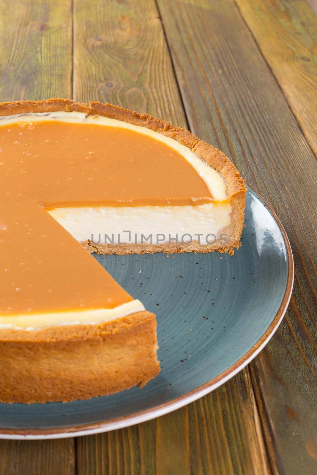 Cut cheesecake on plate on wooden table close up
